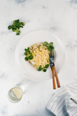 Makarna otlar ve beyaz tabak içinde parmesan peyniri ile