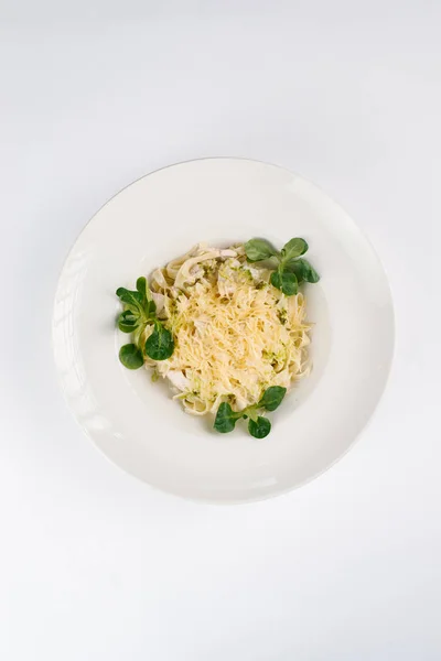 Pasta with herbs and parmesan cheese in white plate