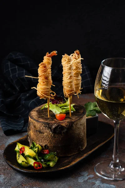 Unusually served snacks with spaghetti and meat on sticks on stump