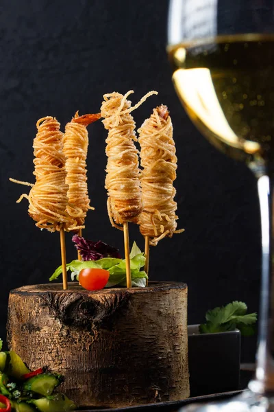 Unusually served snacks with spaghetti and meat on sticks on stump