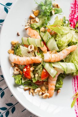 Salata sebze, karides ve beyaz tabakta fındık kesilmiş