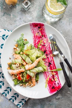 Salata sebze, karides ve beyaz tabakta fındık kesilmiş