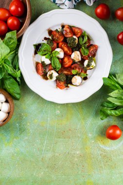 Domatesli taze İtalyan salatası, mozzarella peyniri ve peso yeşil eski püskü masada beyaz tabakta servis edilir.