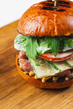 Beyaz arka planda domates ve sığır etli lezzetli bir hamburger.