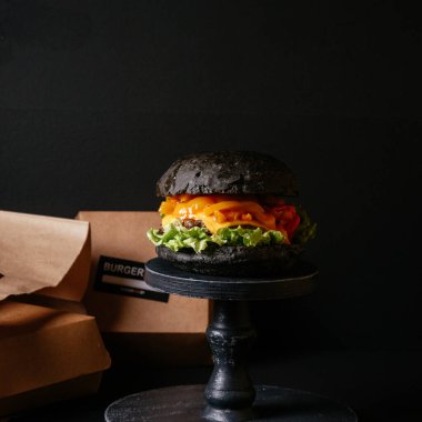 Sebzeli, peynirli, soğanlı ve ahşap ekmekli leziz et burgerini yakın plan. 