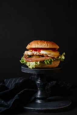 Sebzeli, pastırmalı ve yumurtalı leziz ızgara sığır burger ve ahşap masa. 
