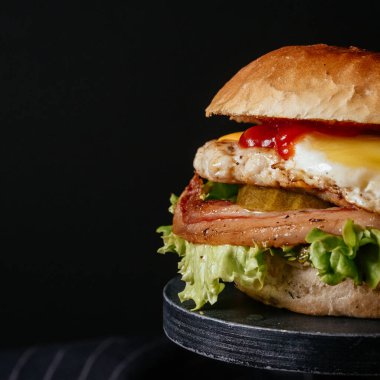 Sebzeli, pastırmalı ve yumurtalı leziz ızgara sığır burger ve ahşap masa. 