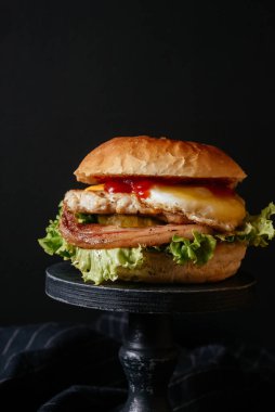 Sebzeli, pastırmalı ve yumurtalı leziz ızgara sığır burger ve ahşap masa. 