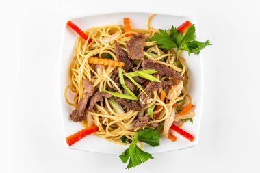 Beyaz arka planda tavuk ve sebzeli spagetti.