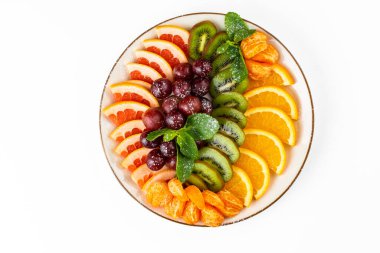 Arka planda beyaz tabakta kesilmiş meyve tabağı