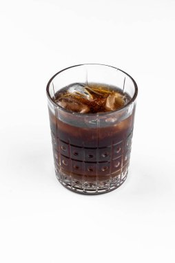 Beyaz masa arkasında rom ve kola ile bir bardak alkollü kokteyl.