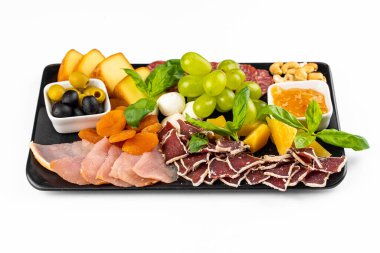 Jambonlu et tabağı ve arka planda üzüm ve sosla süslenmiş et dilimleri.