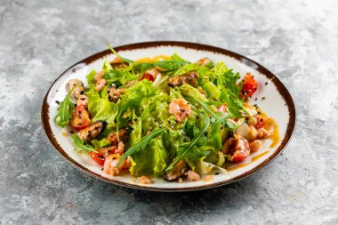 yeşil salata tabağı ile ton balığı dilimleri, domatesler ve soğanlar gri masa arkasında