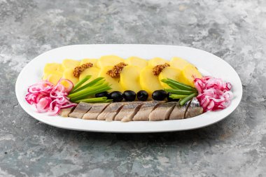 Elmalı ringa ve tatlı soğan halkaları, yeşillik ve ahşap tabakta marul.