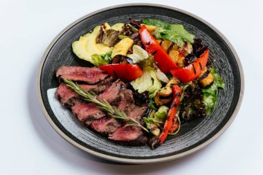 Izgara sebzeler ve siyah tabakta ızgara et. 