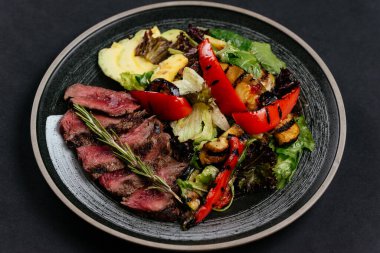 Izgara sebzeler ve siyah tabakta ızgara et. 