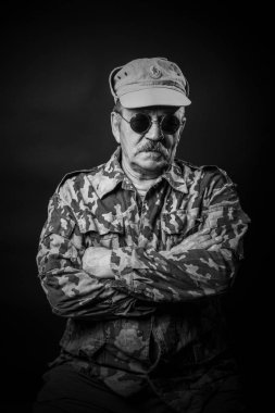 Gözlüklü ve kamuflajlı yaşlı adam.
