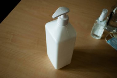 Sıvı sabun için, duş jeli için, kalın bir antiseptik için beyaz plastik dağıtıcının üst görüntüsü. Sıvı sabun ya da antiseptik için beyaz uzun bir kap. Masada beyaz, uzun bir şeker kutusu var. Duş jeli, şampuan kabı.