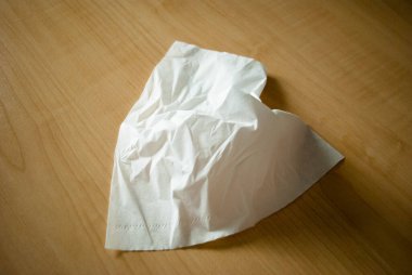 Masadaki beyaz dokunun görüntüsü. Beyaz peçete açıldı. Üşütürken doku kullanmak. Göz yaşları için mendil. 