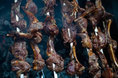 Metal bir şişte barbekü yapmak. Barbeküde ızgara et. Dilimlere kesilmiş taze et şişleri. Geleneksel doğu yemeği, barbekü. Kömür ve alev ızgarası, piknik, sokak yemeği.