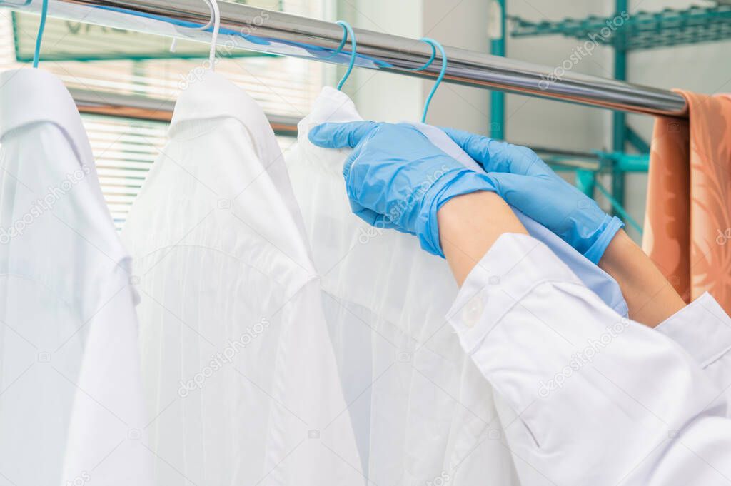 Woman hangs freshly clean washed white shirts to dry. Ecological washing