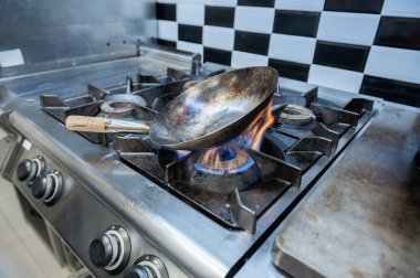 Restoranın mutfağında metalik tencere ısıtılıyor.