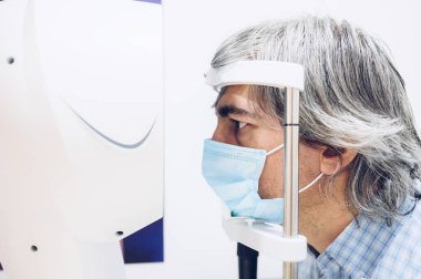 Göz doktorunun ofisinde görme testi yaptıran orta yaşlı bir adam. Vizyon tedavisi konsepti.