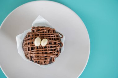 Turkuaz arka planda beyaz bir tabakta ev yapımı çikolatalı kek. Boşluğu kopyala. Ev yapımı gıda konsepti.