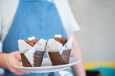 Bir kahvehane garsonu elinde iki tane iştah açıcı kek tutuyor. Kopya yeri. Güzel anlar. Küçük işletme kavramı.