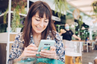 Genç, güzel bir kız arkadaşlarıyla buluşurken akıllı telefonuna bakıp gülümsüyor.