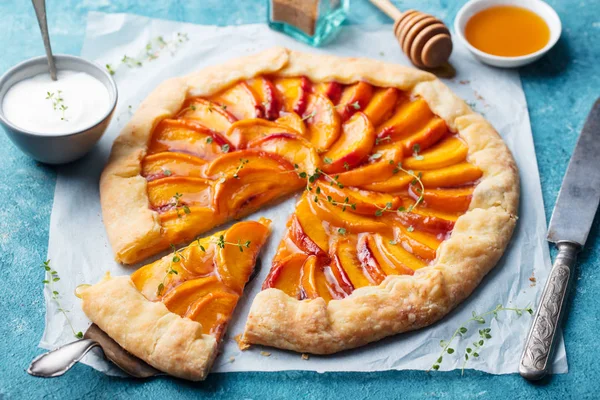 Peach galette, pie, cake with honey and berry on a blue background.