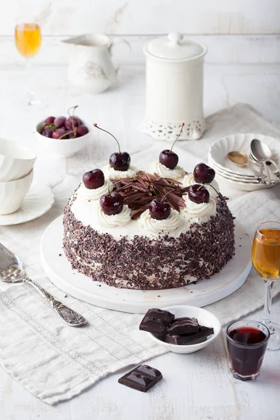 Black forest cake, Schwarzwald pie, dark chocolate and cherry dessert on a white wooden cutting board.
