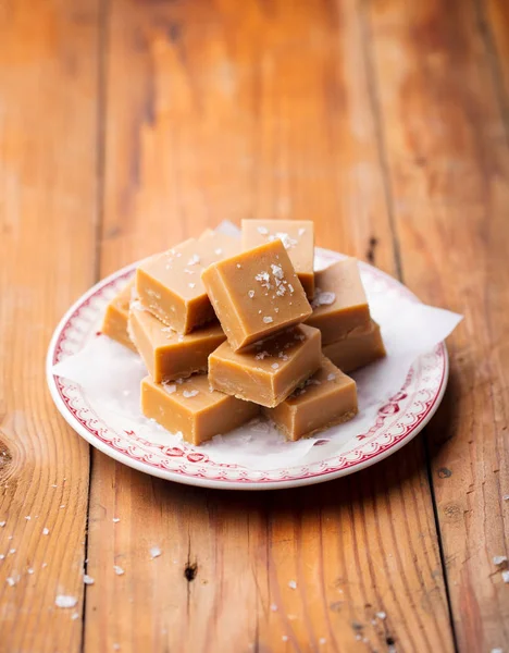 Fresh caramel fudge candies on a plate. Wooden background. Copy space.