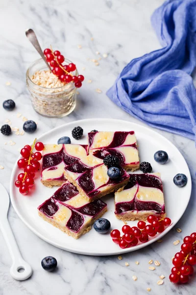 Oatmeal, oat bars with fresh berries on a white plate. Marble background. Top view.