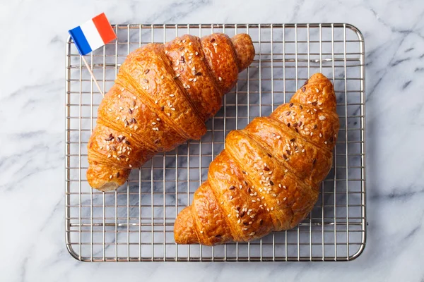 Croissants with French flag on cooling rack. Marble background. Top view.