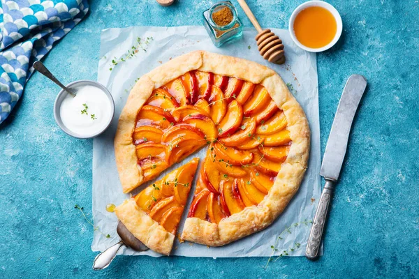 Peach galette, pie, cake with cream on blue background. Top view.