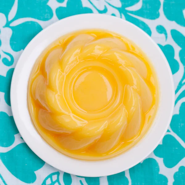Mango pudding, jelly on white plate Blue textile background. Top view. Copy space.