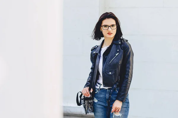 シンプル背景で路上のレザー ジャケットのメガネの女 — ストック写真