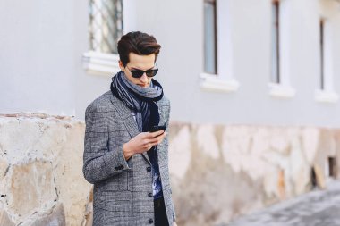 Güneş gözlüğü ile telefon şık genç adam sokakta yürümek
