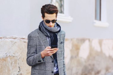 Güneş gözlüğü ile telefon şık genç adam sokakta yürümek