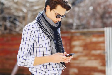 Güneş gözlüğü ile telefon şık genç adam sokakta yürümek