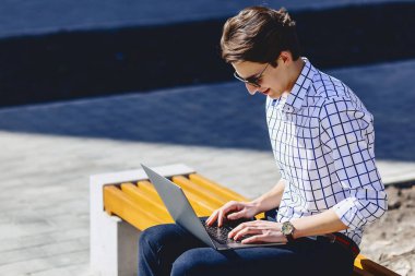 Telefon şık genç adamla iş üstünde laptop Park'ta güneşli günde