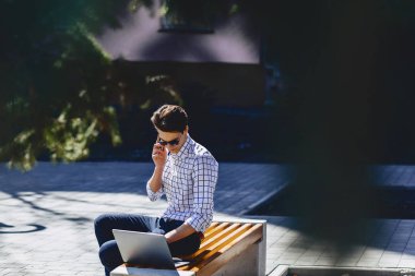 Telefon şık genç adamla iş üstünde laptop Park'ta güneşli günde