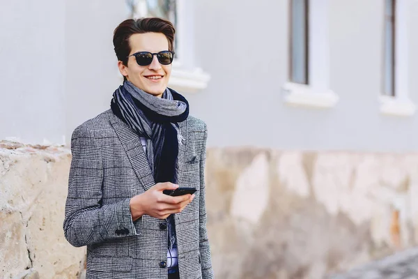 Güneş gözlüğü ile telefon şık genç adam sokakta yürümek