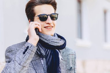 Güneş gözlüğü ile telefon şık genç adam sokakta yürümek
