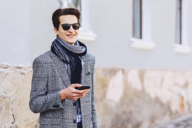 Güneş gözlüğü ile telefon şık genç adam sokakta yürümek