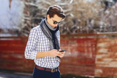 Güneş gözlüğü ile telefon şık genç adam sokakta yürümek