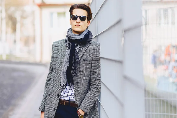 Stylish boy in sunglasses in coat with briefcase on street outside