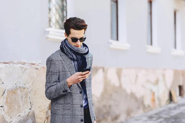 Güneş gözlüğü ile telefon şık genç adam sokakta yürümek