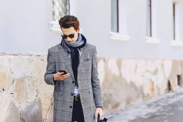 Güneş gözlüğü ile telefon şık genç adam sokakta yürümek